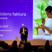 Picture of a male speaker from Tietoevry in front of big screen on stage