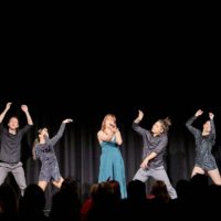 Four dancers and a singer is performing on stage